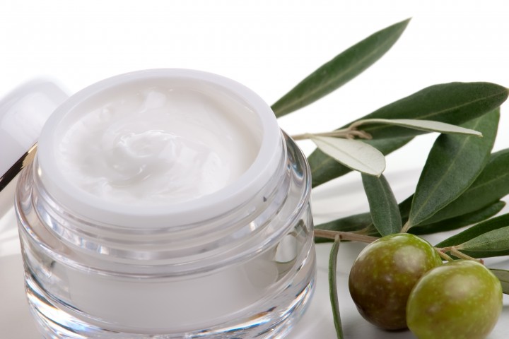 closeup of jar of moisturizing face cream and twig with green olives