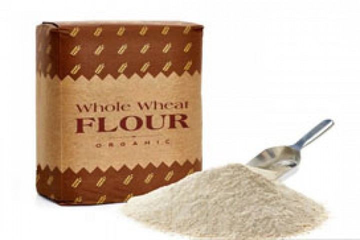 whole flour in craft paper bag with flour pile on white background