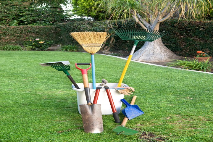 yard working and gardening tools on green grass and a well groomed yard